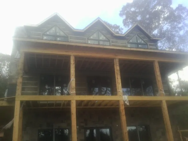 Dormers and porch framing on a large log home under construction — Roof Coating work by our crew in La Push