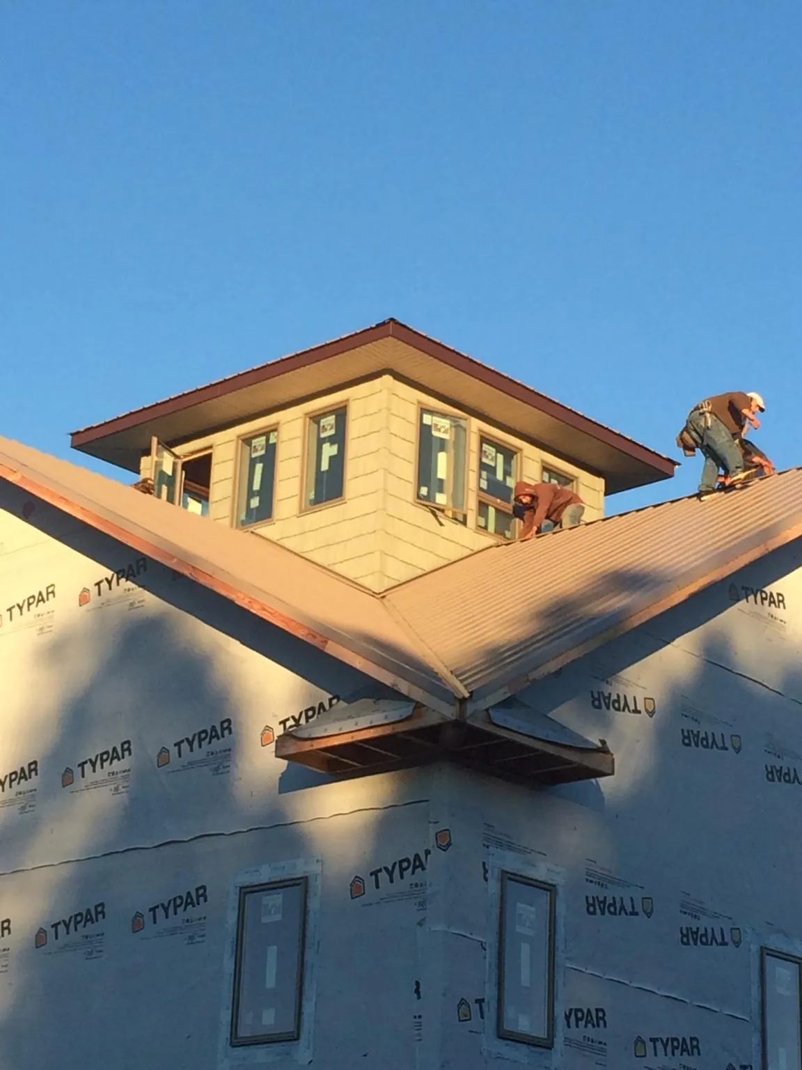 Roofers working around a rooftop cupola on a new metal roof at sunset — Roof Waterproofing in La Push by Roofing Brothers